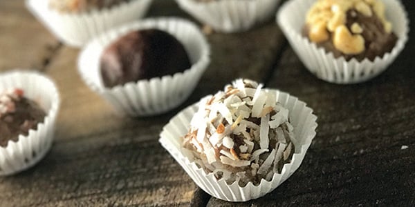 photo of chocolate peanut butter protein truffles in white paper cups sitting on wooded counter