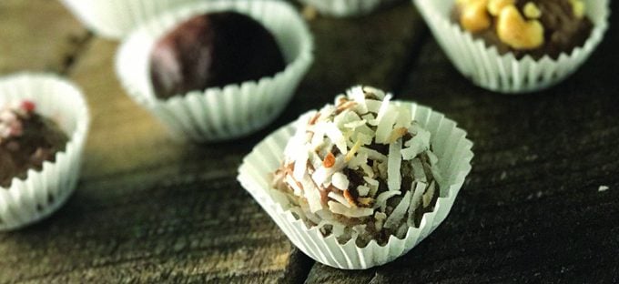 photo of chocolate peanut butter protein truffles in white paper cups sitting on wooded counter