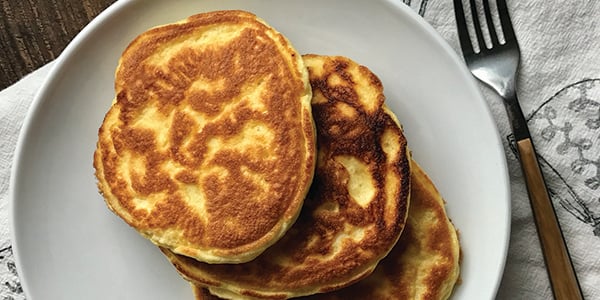 overhead photo of three high protein pancakes on a white plate